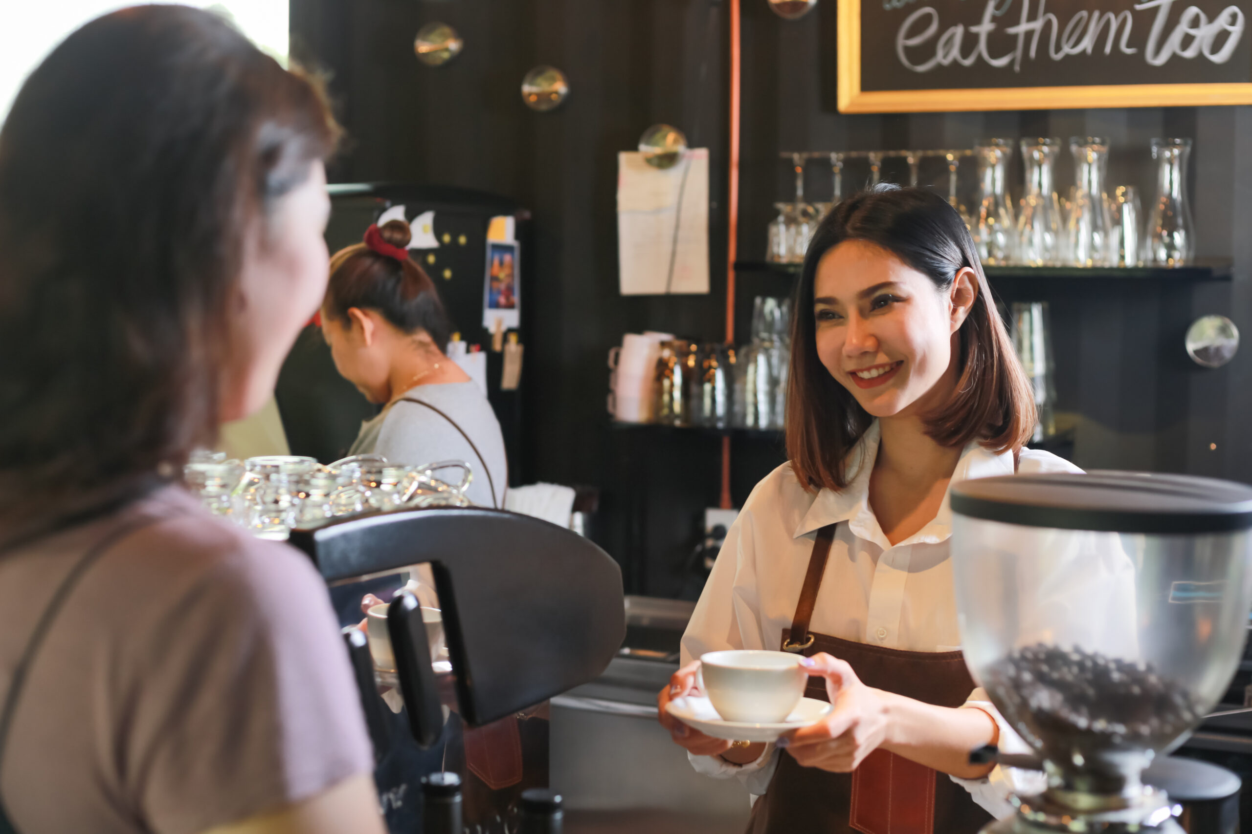 Young,Female,Barista,Serving,Coffee,To,Customer,In,Cafe.